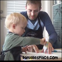 Two-year-old Logan makes a spiral snake with his dad.